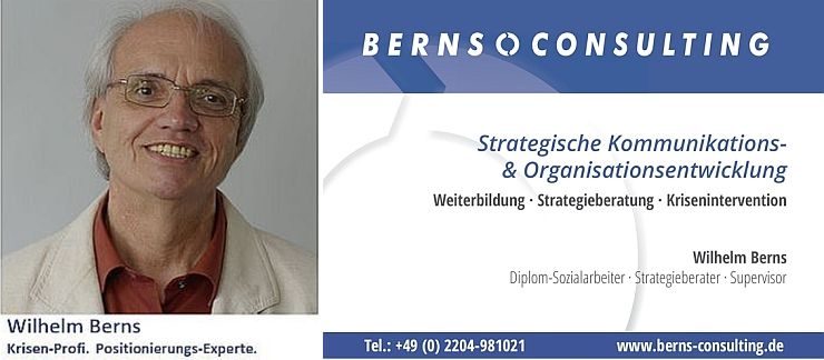 zeigt Wilhelm Berns mit dem Türschild zur Strategischen Kommunikations- und Organisationsentwicklung der Praxis für Krisenberatung